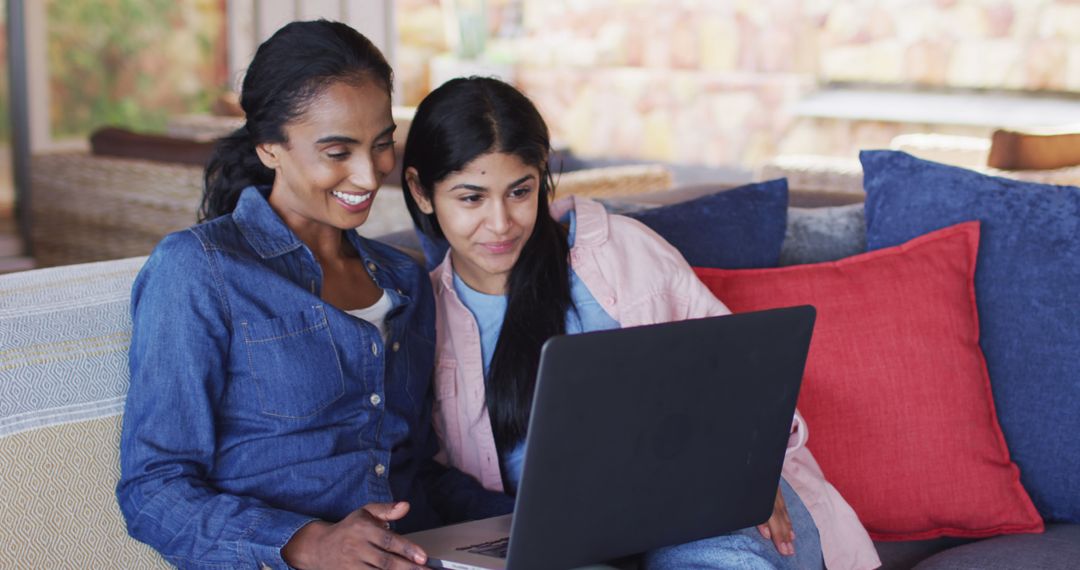 Two Women Smiling While Using Laptop on Couch - Free Images, Stock Photos and Pictures on Pikwizard.com