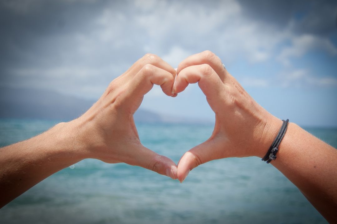 Hands Forming Heart Shape on Seaside