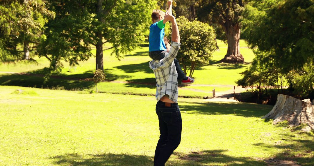 Father Carrying Child on Shoulders in Sunny Park - Free Images, Stock Photos and Pictures on Pikwizard.com