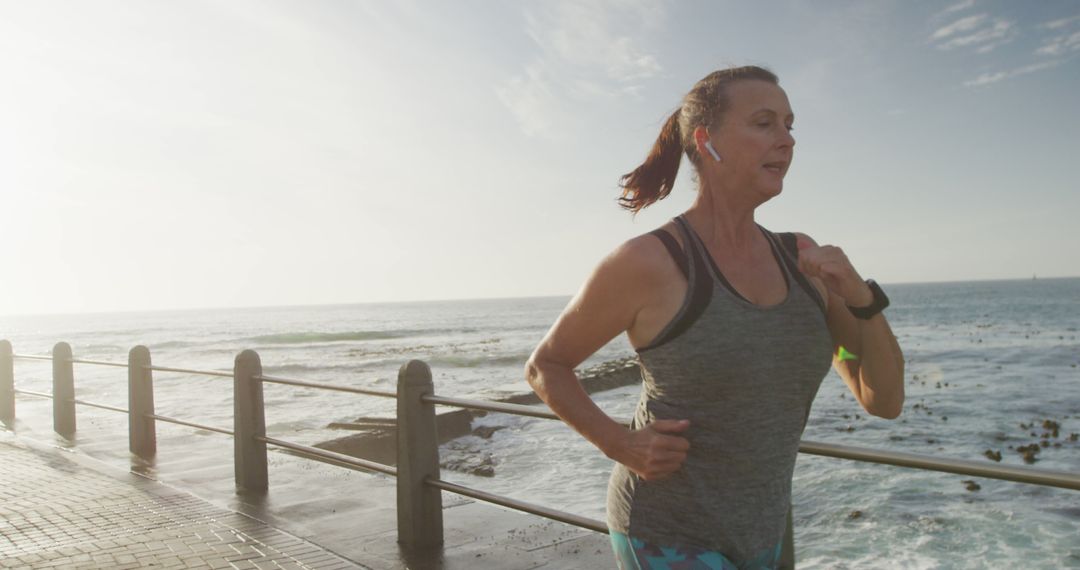 Senior Woman Jogging by the Sea and Wearing Wireless Earbuds - Free Images, Stock Photos and Pictures on Pikwizard.com