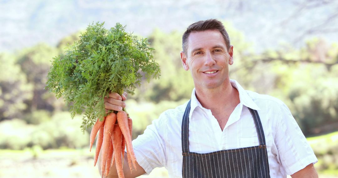 Happy Farmer Holding Freshly Harvested Organic Carrots Outdoors - Free Images, Stock Photos and Pictures on Pikwizard.com