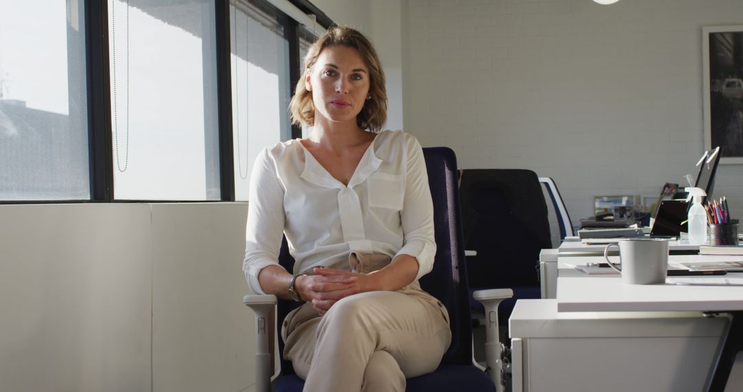 Confident Businesswoman Sitting in Modern Office - Free Images, Stock Photos and Pictures on Pikwizard.com