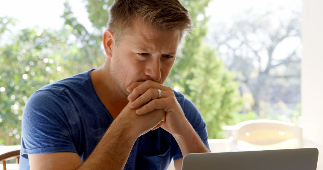 Concerned middle-aged man intently reading at laptop