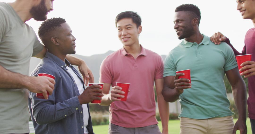 Diverse friends socializing outdoors holding red cups - Free Images, Stock Photos and Pictures on Pikwizard.com