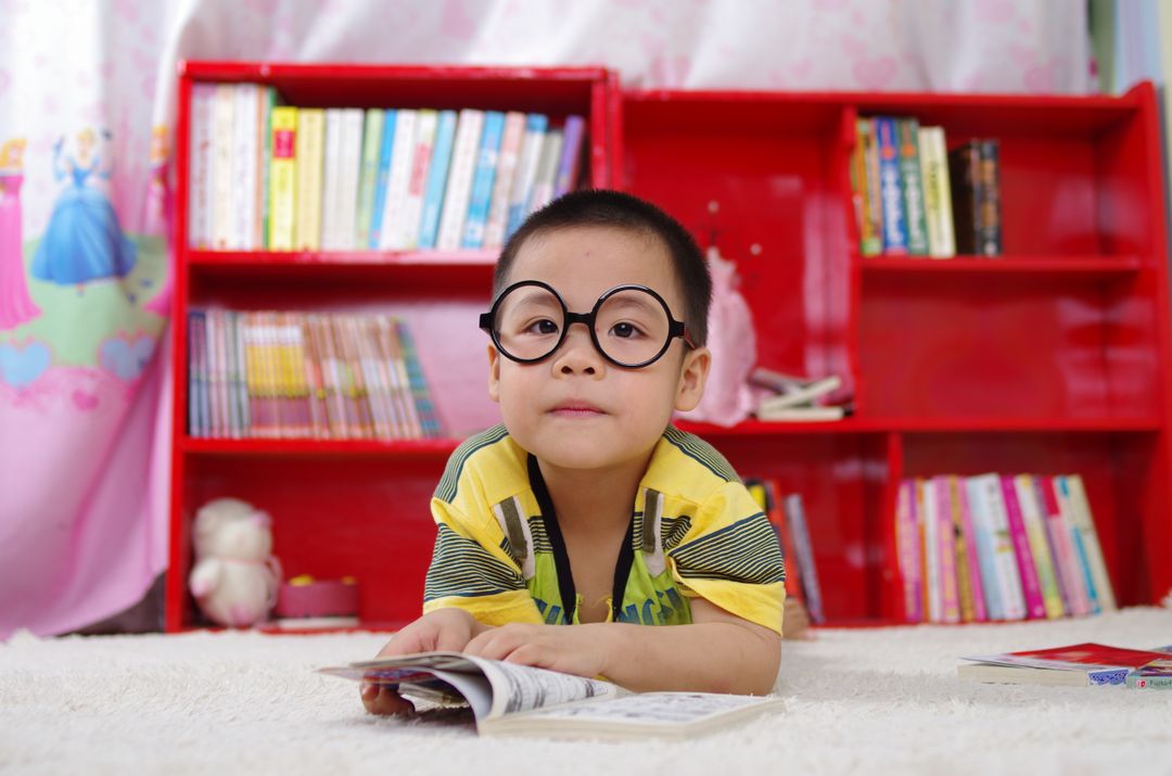 Young Boy Reading Book with Toy Shelves in Background - Free Images, Stock Photos and Pictures on Pikwizard.com