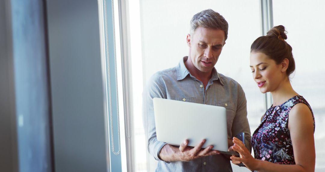 Executives Collaborating in Modern Office with Laptop