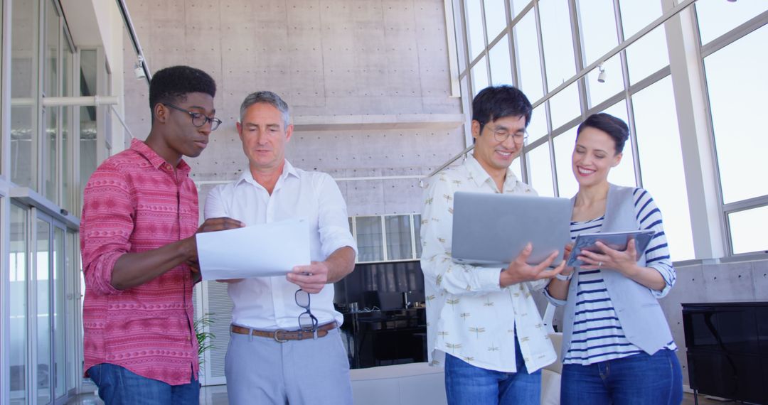 Diverse Team Collaborating with Documents and Laptops in Modern Office