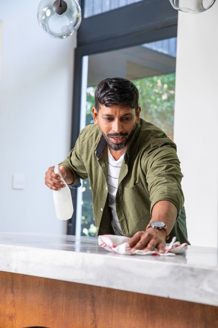 Man Cleaning Marble Countertop at Home