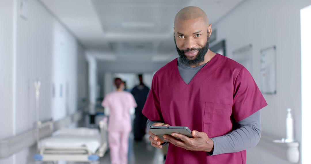 Confident Male Nurse Using Digital Tablet in Hospital Corridor - Free Images, Stock Photos and Pictures on Pikwizard.com