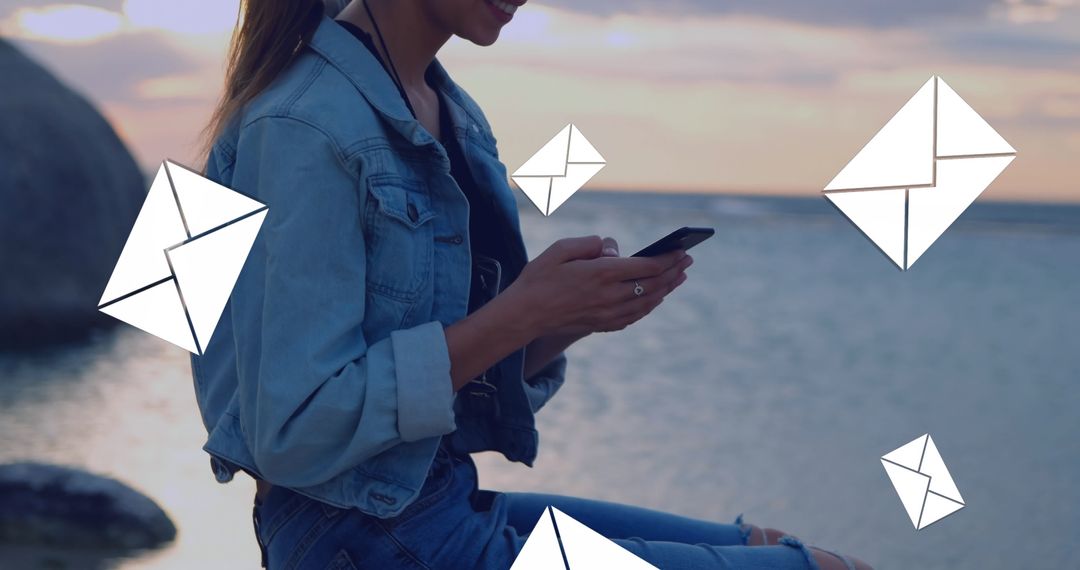 Woman Texting by Ocean with Flying Message Icons at Sunset