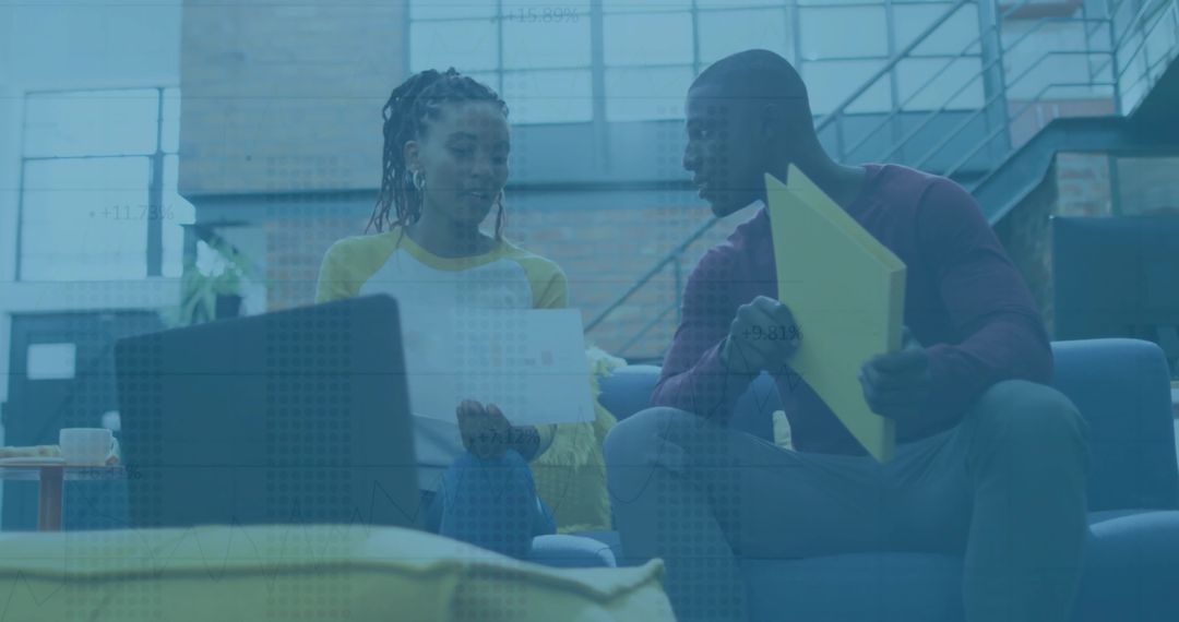 Two Colleagues Collaborating on Blue Sofa in Modern Office Setting