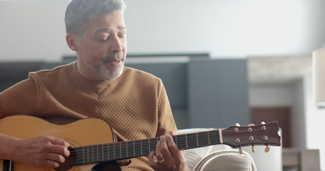 Older man playing acoustic guitar in living room - Free Images, Stock Photos and Pictures on Pikwizard.com