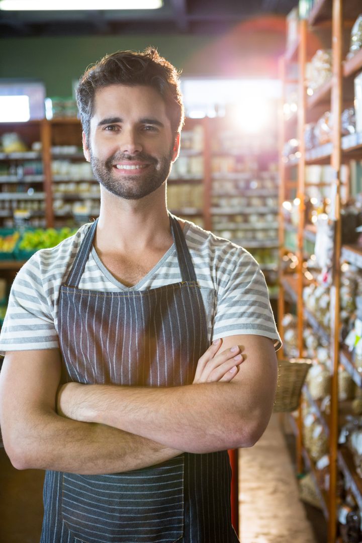 Smiling Male Store Clerk in Rustic Grocery Aisle Wearing Apron
