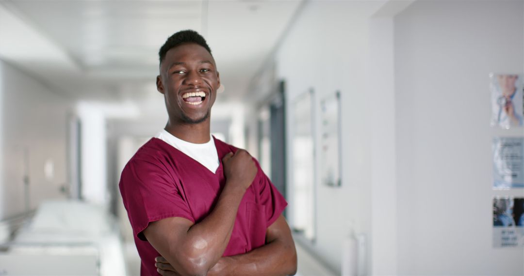 Smiling Health Professional Wearing Burgundy Scrubs in Hospital Corridor - Free Images, Stock Photos and Pictures on Pikwizard.com