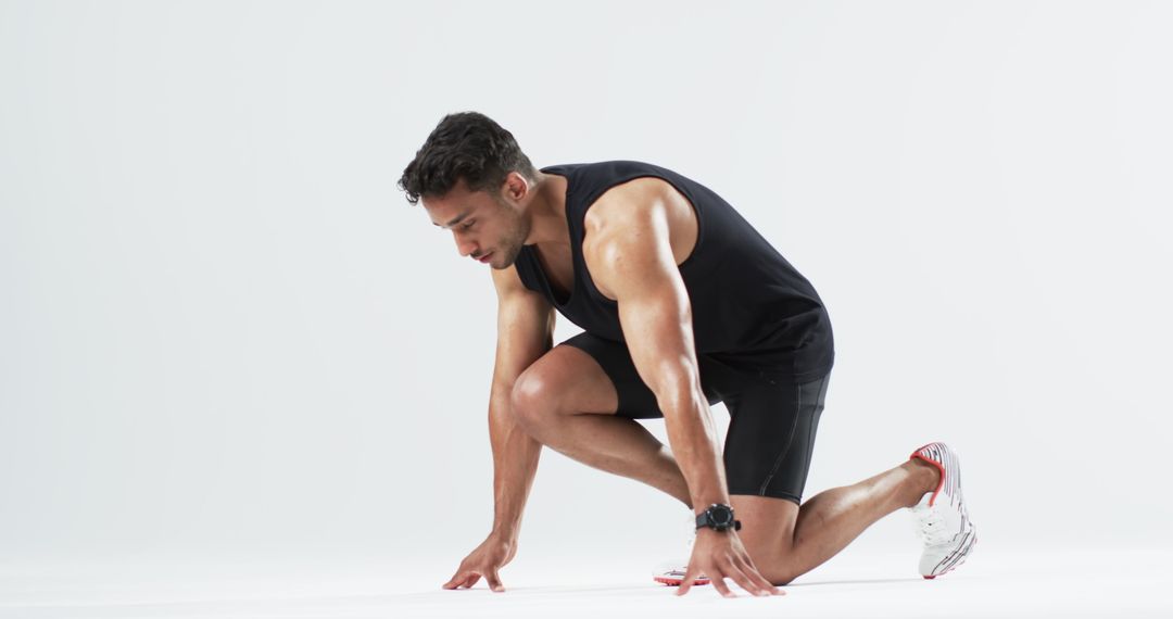Athletic Biracial Man Preparing for Sprint in Studio