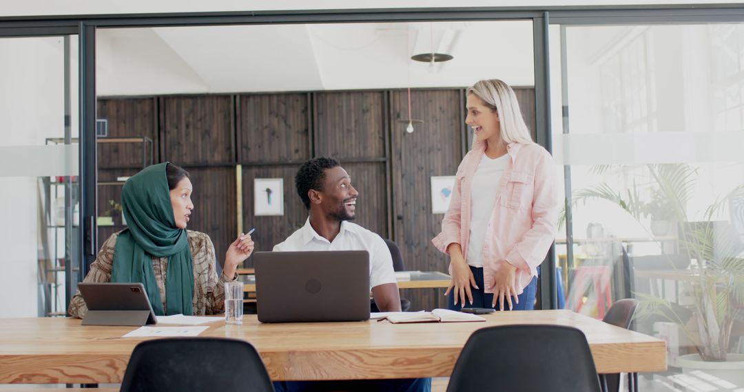 Diverse Team Engaged in Casual Meeting with Laptops at Office Table