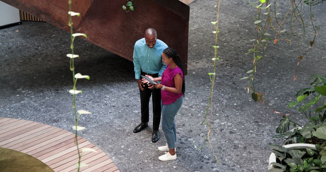 Colleagues Collaborating with Tablet in Modern Office Courtyard