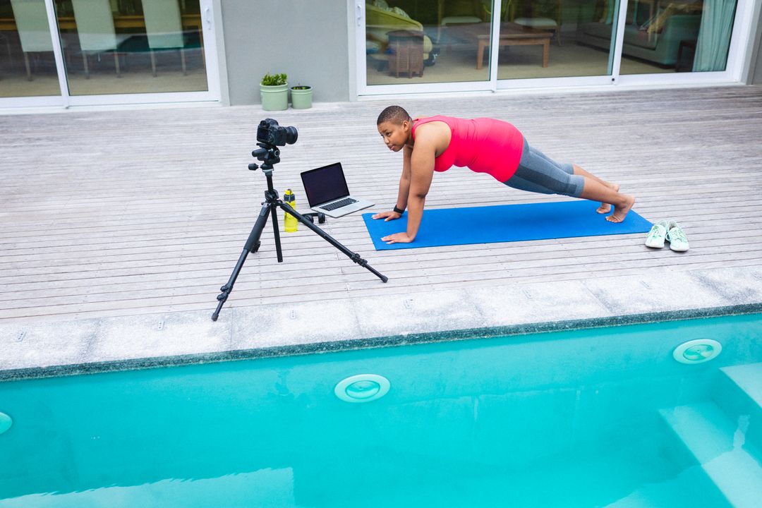 African american female blogger recording a video on digital camera while exercising by the pool - Free Images, Stock Photos and Pictures on Pikwizard.com