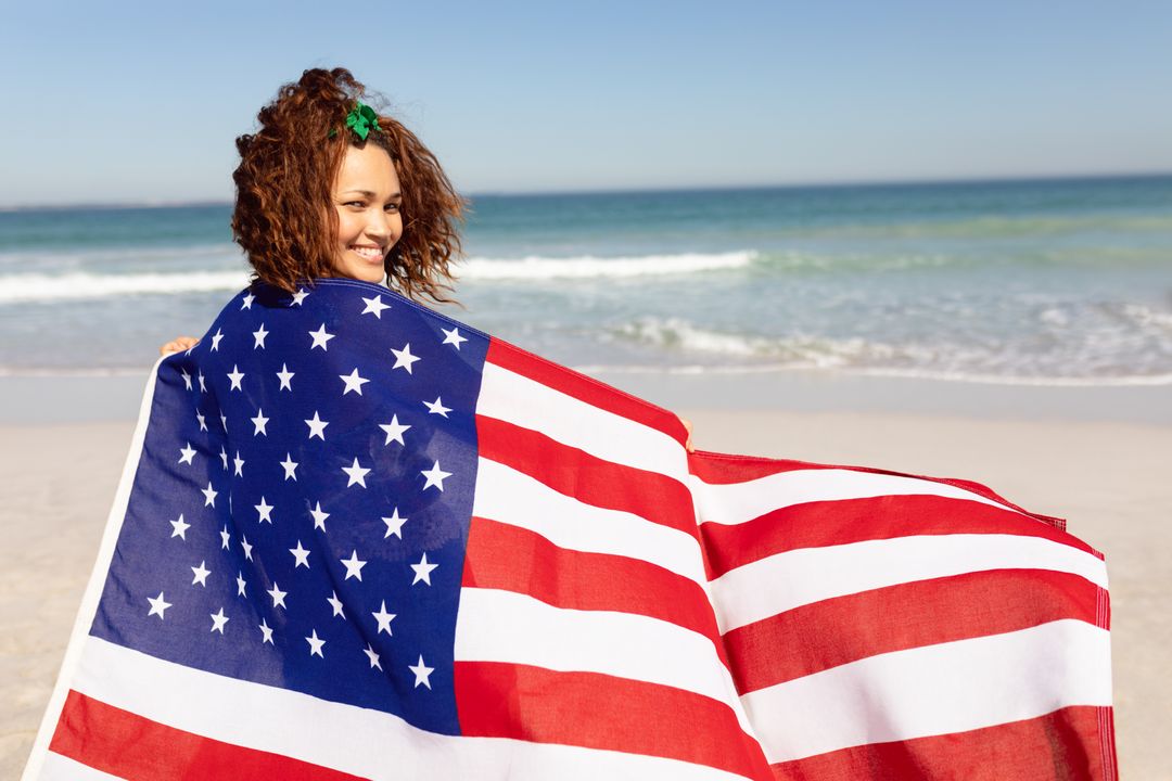 Biracial Woman Holding American Flag on Beach - Free Images, Stock Photos and Pictures on Pikwizard.com