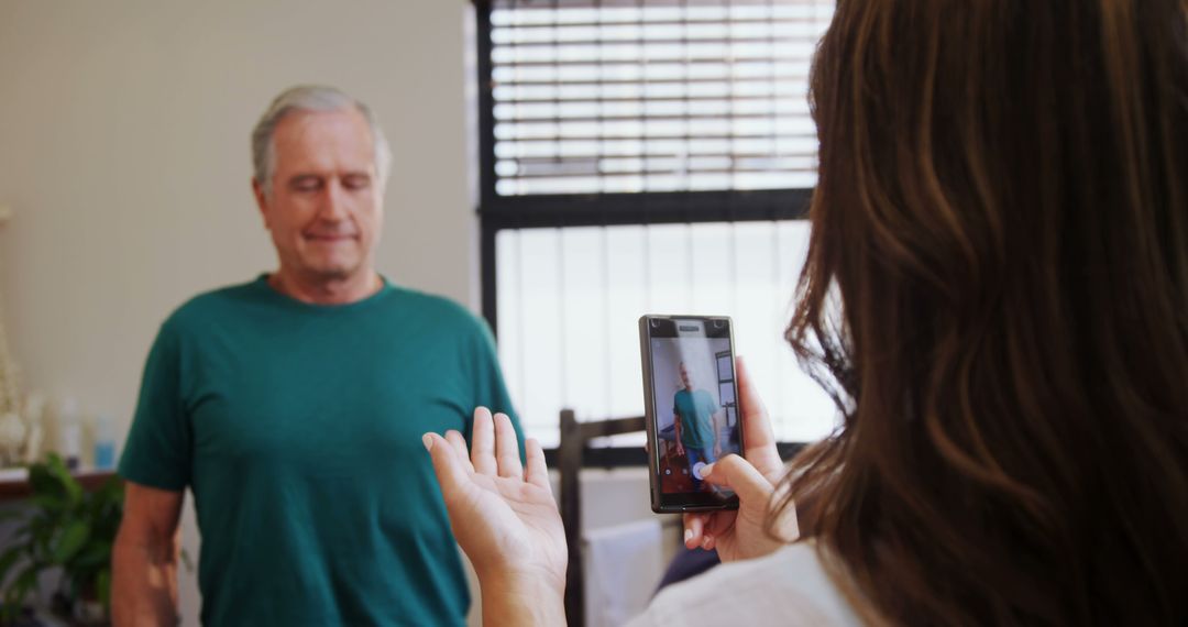 Woman Using Smartphone to Record Senior Man in Casual Setting - Free Images, Stock Photos and Pictures on Pikwizard.com