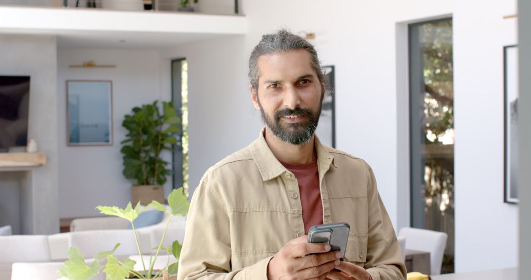 Man Holding Smartphone in Modern Home Interior