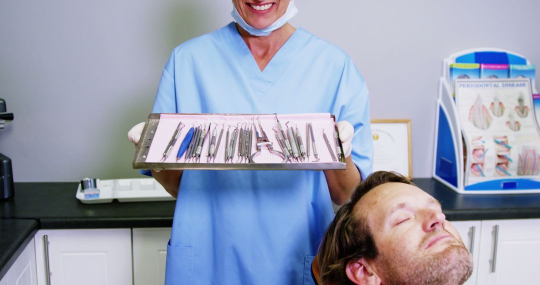 Dentist Holding Tray of Dental Instruments While Male Patient Prepares for Treatment - Free Images, Stock Photos and Pictures on Pikwizard.com