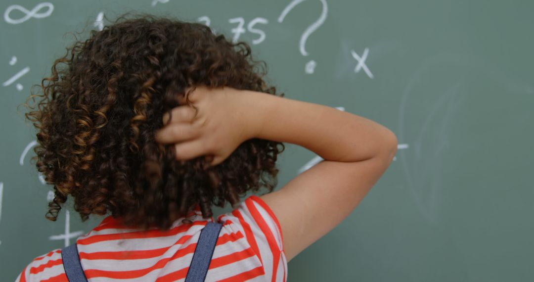 Confused Student Scratching Head in Front of Chalkboard