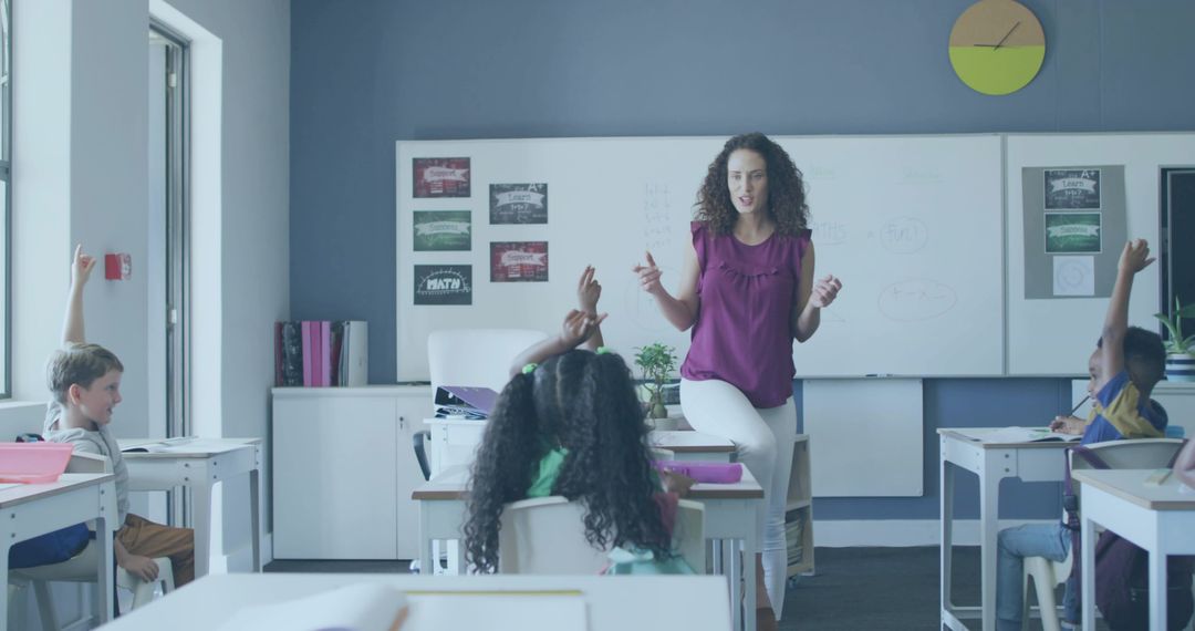 Elementary teacher leading interactive classroom lesson with students raising hands