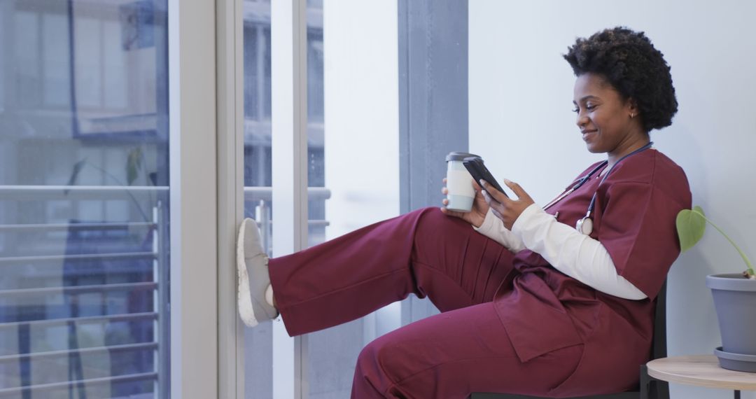 Female Nurse Relaxing in Scrubs, Holding Coffee and Tablet by Window - Free Images, Stock Photos and Pictures on Pikwizard.com