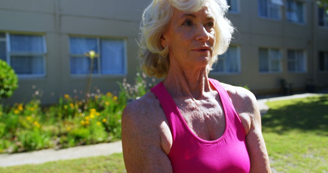 Senior Woman Exercising with Dumbbells on Exercise Ball in Garden