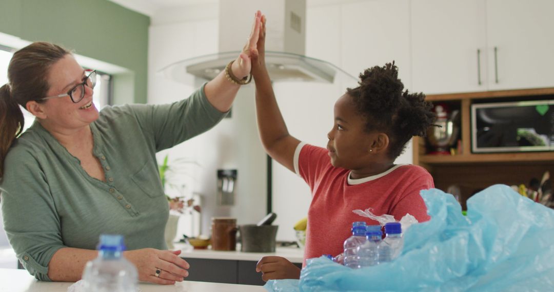 Mother and Daughter High-Fiving While Sorting Waste in Kitchen