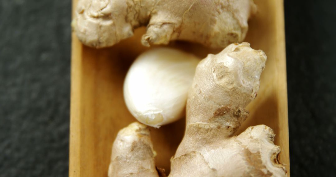 Ginger Roots and Garlic Clove on Wooden Tray Against Dark Background - Free Images, Stock Photos and Pictures on Pikwizard.com