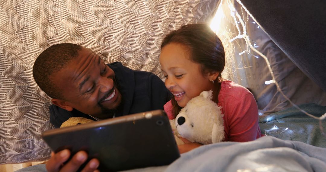 Happy Father and Daughter Reading on Tablet in Homemade Fort - Free Images, Stock Photos and Pictures on Pikwizard.com