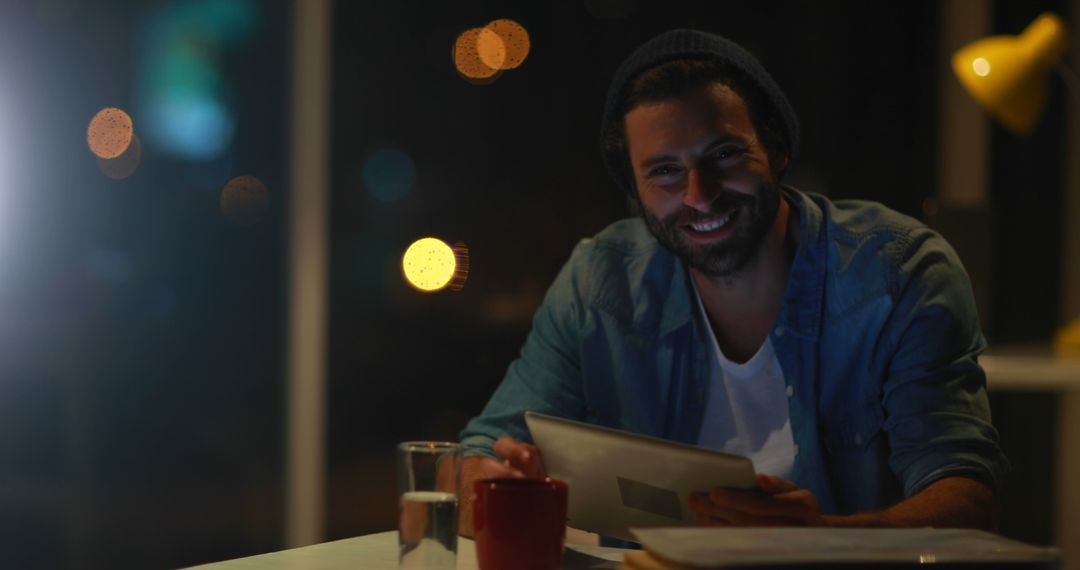 Smiling Man Using Tablet at Night in Modern Workspace - Free Images, Stock Photos and Pictures on Pikwizard.com