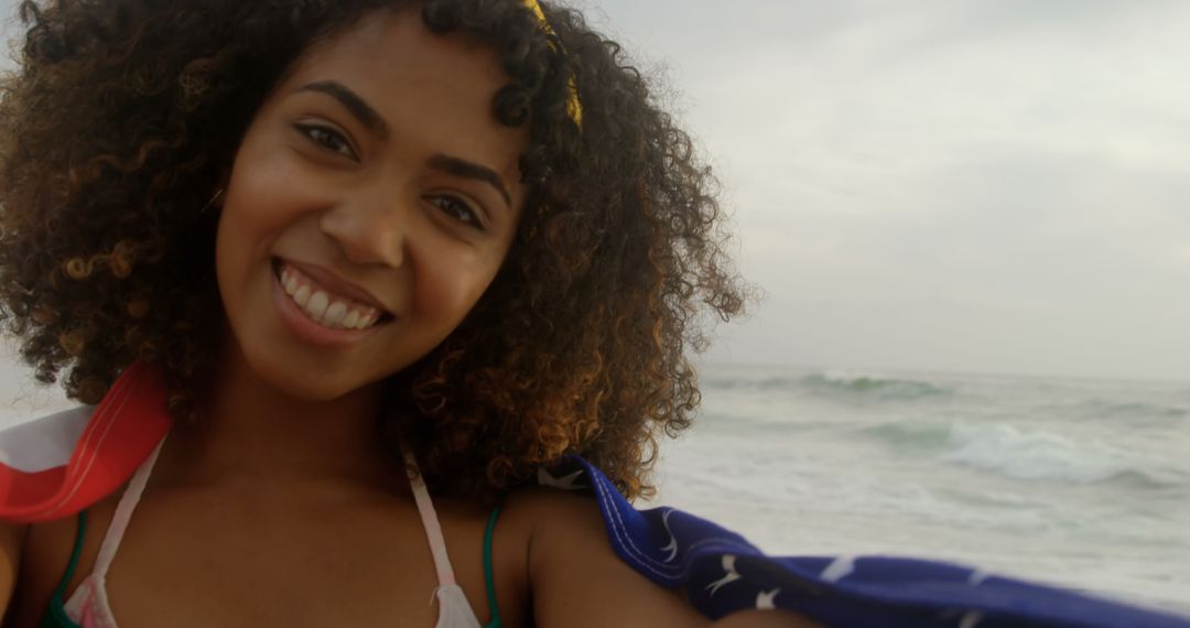 Smiling Woman Wrapped in American Flag Standing at the Beach