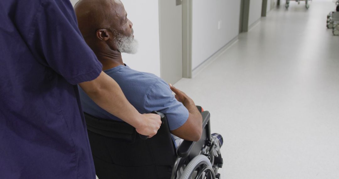 Healthcare Worker Assisting Elderly Patient in Wheelchair in Hospital Corridor - Free Images, Stock Photos and Pictures on Pikwizard.com