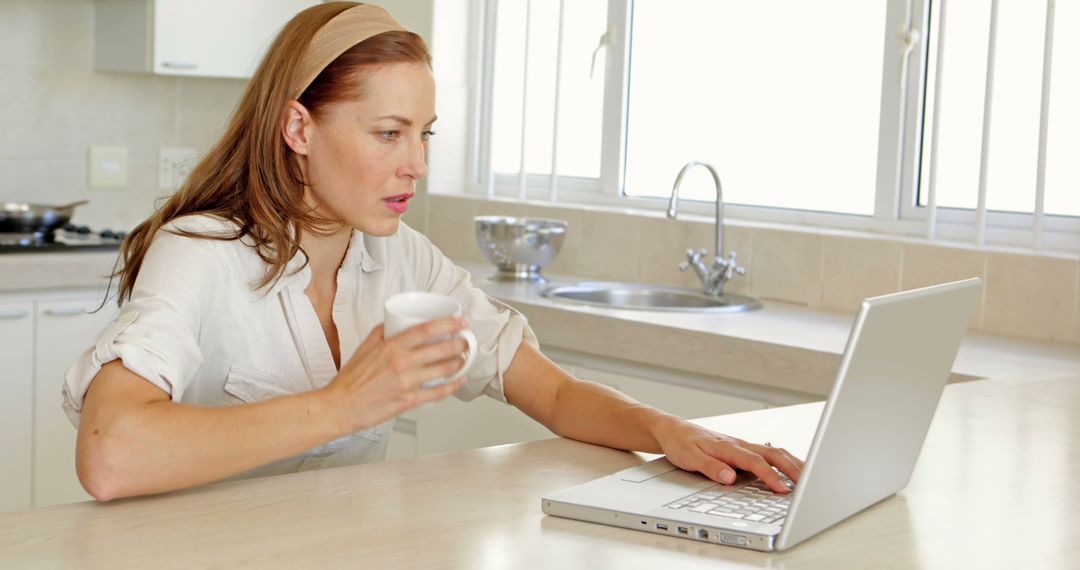 Woman Drinking Coffee While Working on Laptop at Home Kitchen - Free Images, Stock Photos and Pictures on Pikwizard.com