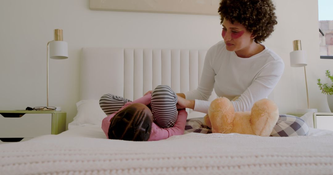 Mother and Daughter Playing in Bedroom with Teddy Bear