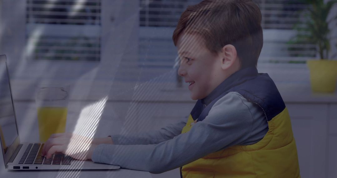 Young Boy Typing on Laptop in Sunlit Kitchen