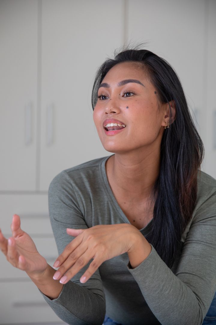 Asian Woman Gesturing Enthusiastically in Modern Kitchen