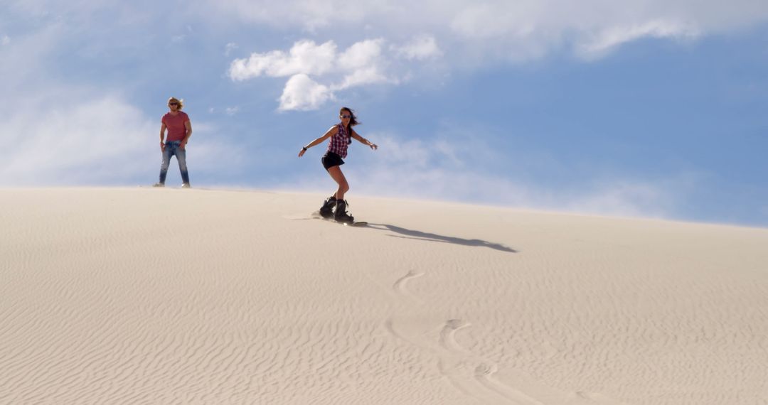 Adventurous Couple Enjoys Sandboarding on Desert Dunes