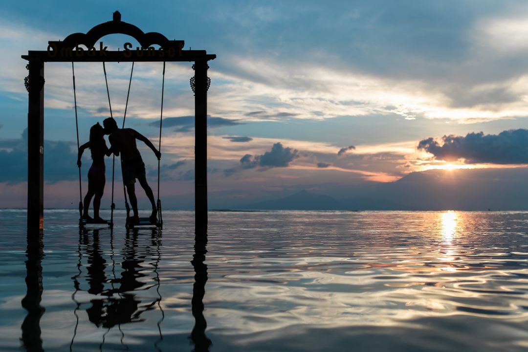 Romantic Couple Enjoys Sunset Silhouette on Swing Over Water - Free Images, Stock Photos and Pictures on Pikwizard.com