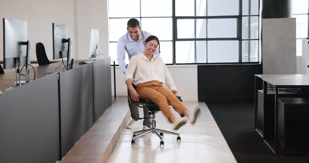 Colleagues Having Fun with Office Chair in Creative Workspace