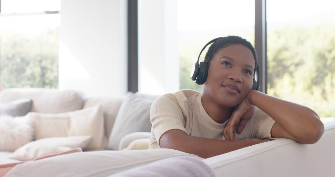 Thoughtful Woman Listening to Music with Headphones in Bright Living Room - Free Images, Stock Photos and Pictures on Pikwizard.com