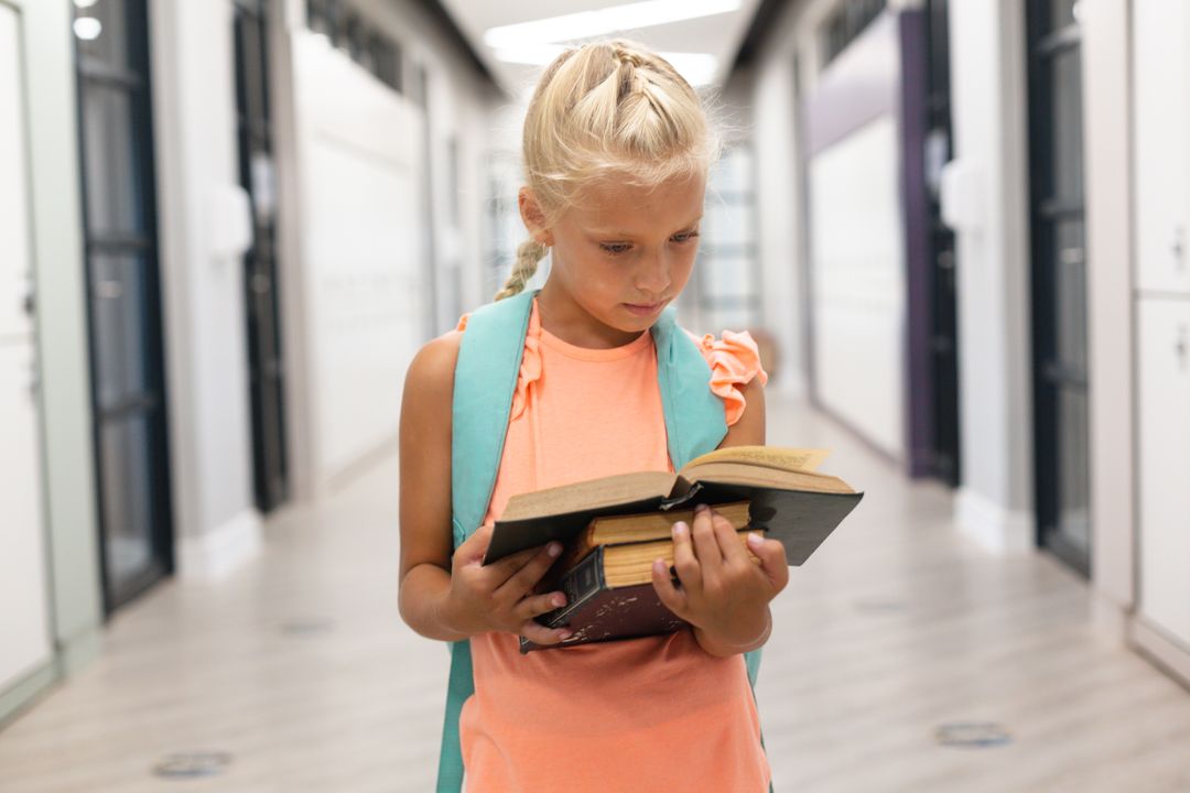 Caucasian Schoolgirl Reading Book in School Corridor - Free Images, Stock Photos and Pictures on Pikwizard.com