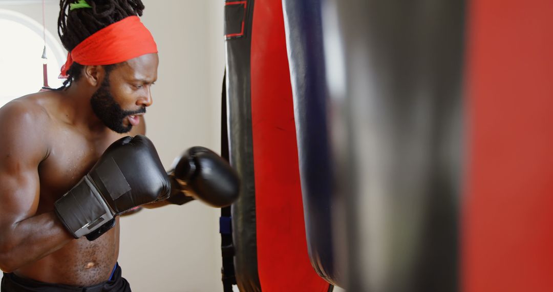 Male Boxer Punching Bag in Intense Training Session at Gym