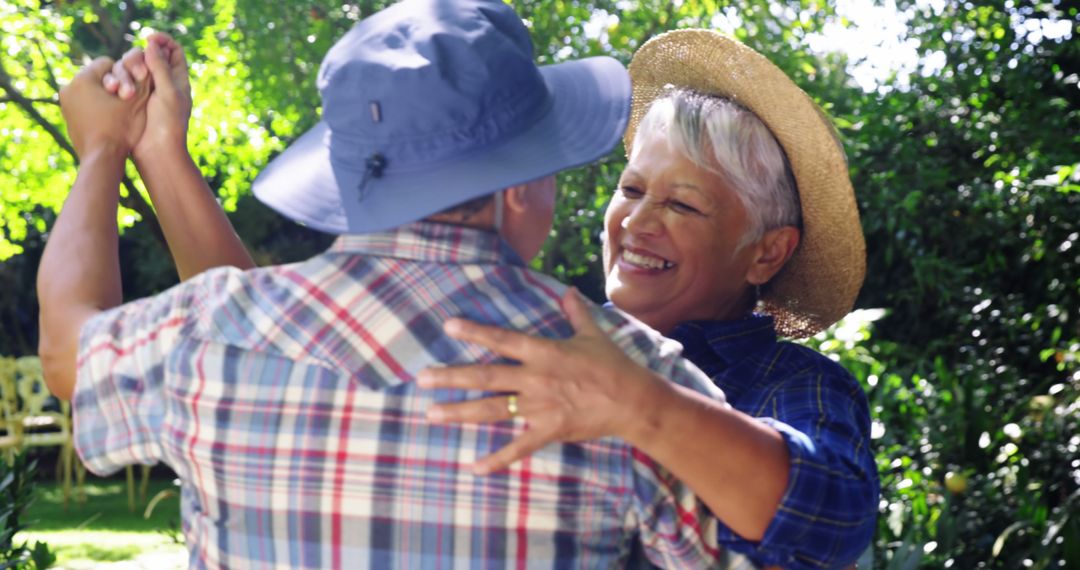 A middle-aged Caucasian couple is joyfully dancing together in a sunny garden, with copy space - Free Images, Stock Photos and Pictures on Pikwizard.com