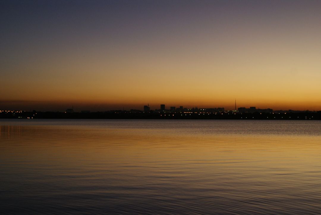 Serene Sunset Over Calm Waters With City Skyline Reflection - Free Images, Stock Photos and Pictures on Pikwizard.com