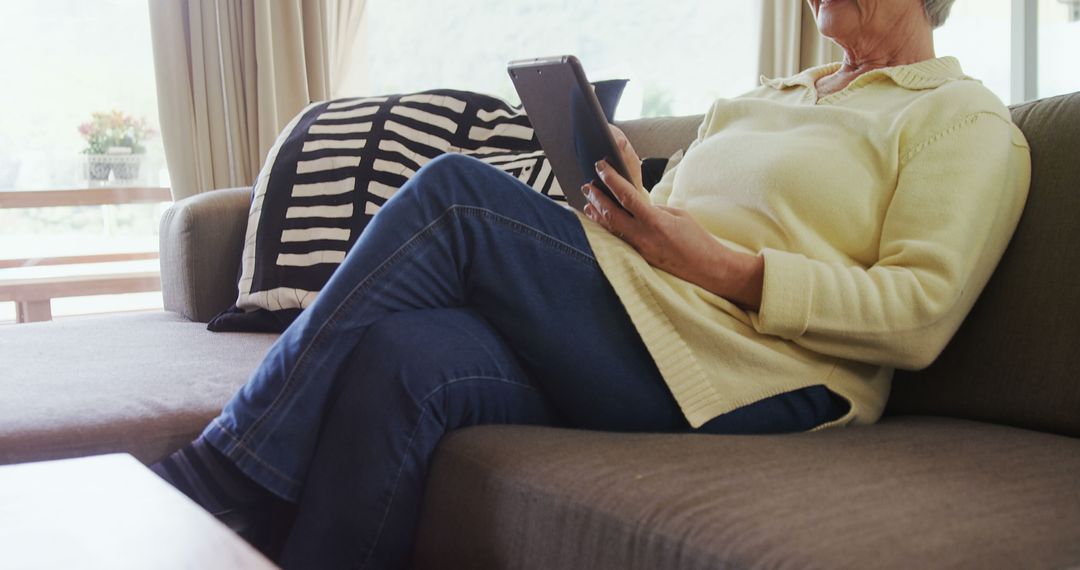 Senior Woman Using Tablet While Relaxing on Couch at Home - Free Images, Stock Photos and Pictures on Pikwizard.com