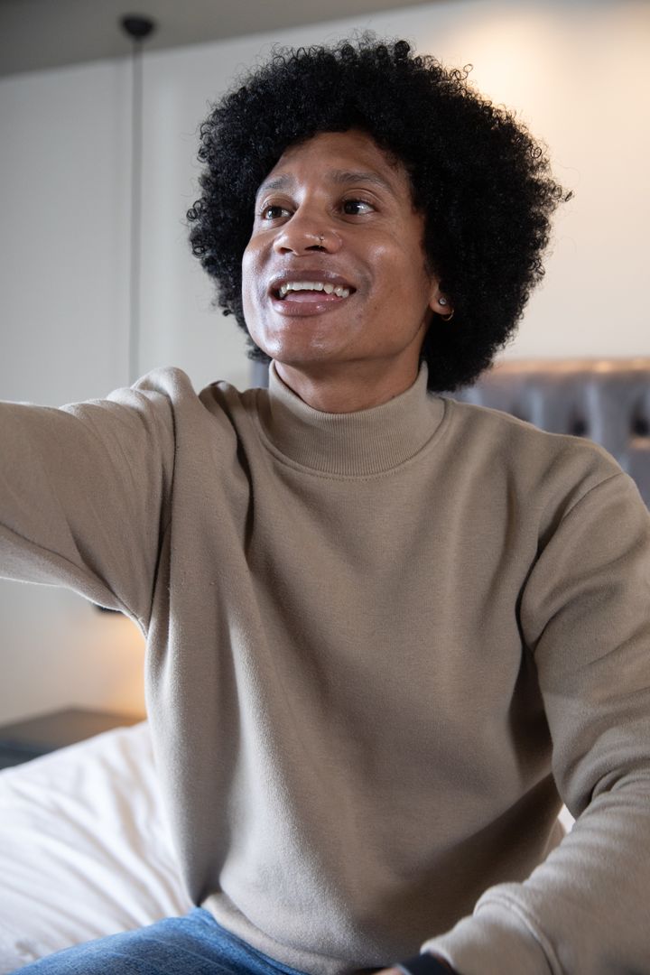 Man Relaxing in Cozy Bedroom, Reaching Forward with Joyful Expression
